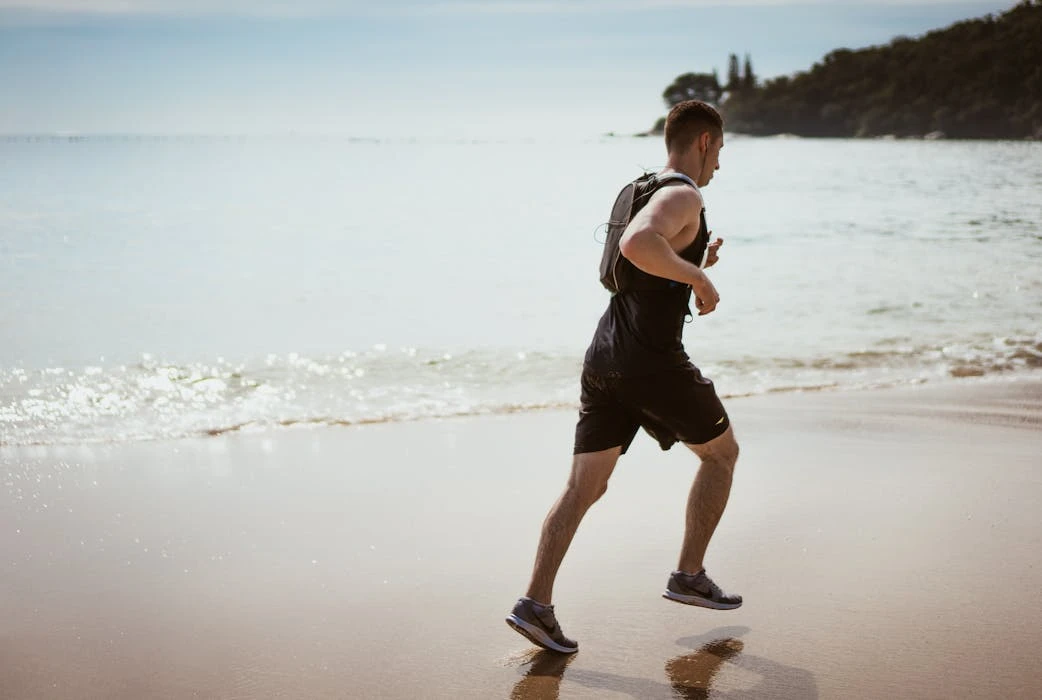 Man running along the beach enjoying fitness and freedom by the ocean waves.